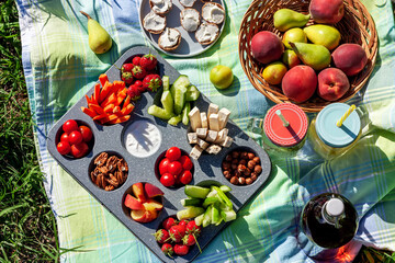 Summertime healthy picnic with fresh vegetables, nuts and fruits served in the muffin pan;...