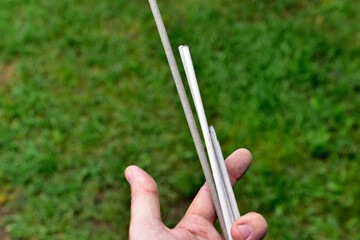 Welding electrodes in hands on a background of grass