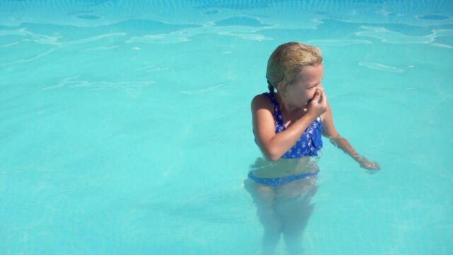 Vacation rest. Swimming in the pool. A cheerful girl dives into the clear water of the hotel pool.