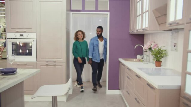 Diverse nan and woman choosing domestic kitchen in studio or furniture store