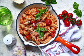 Fusilli pasta with tomatoes and garlic in a skillet. Top view with copy space.