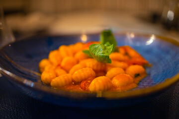 Selective focus on a plate of gnocchi with tomato sauce and abasil leaf. Concept of Mediterranean cuisine, healthy and tasty