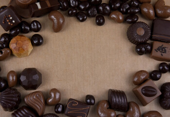 Chocolate pralines frame top view stock images. Chocolate candies on a brown background. Chocolate frame top view. Chocolate pralines background with copy space for text. Border of different pralines