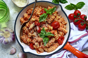 Fusilli pasta with tomatoes and garlic in a skillet. Top view with copy space.