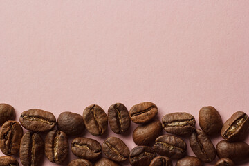 Coffee beans laid out on a pink background