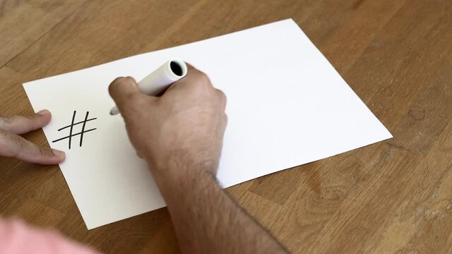 Man writing on a white paper Say No To Racism's hashtag. Slow-motion shooting.