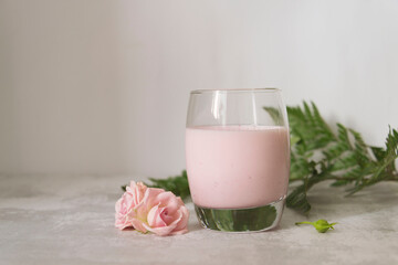 glass of  pink milk with flowers on the white background.