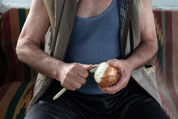A man peels onions for a salad. Onions are grown in your garden.