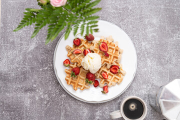 Viennese waffles with ice-cream and strawberries with cup of coffee. Top view. Grey background.