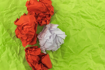Three red heavily crumpled sheets of paper and one sheet of white lie on mint-colored paper