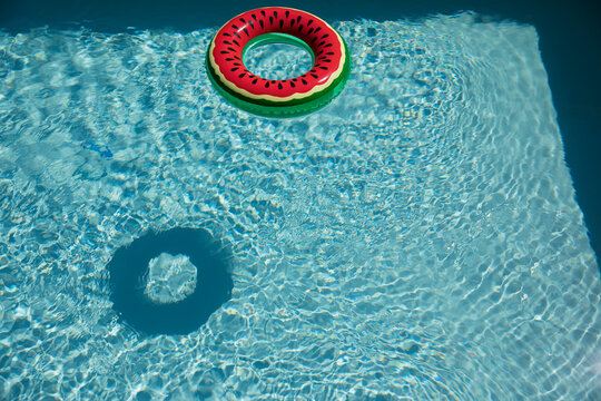 Watermelon inflatable ring in sunny blue summer swimming pool