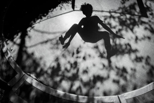 Shadow of boy jumping on sunny trampoline