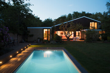 Home showcase exterior with illuminated swimming pool at night