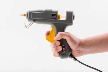 Hand holding a hot glue gun, isolated on white background