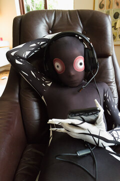 Boy in alien costume wearing headset in leather chair