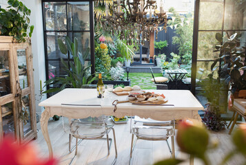 Wine and pizza ingredients on table open to idyllic patio