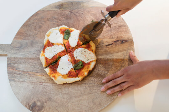 Woman slicing fresh homemade pizza on cutting board