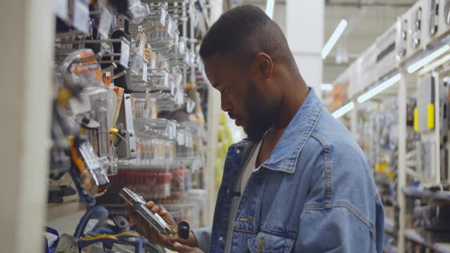Side view of african guy choosing construction staple in diy store