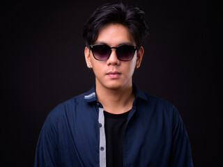 Obraz premium Young handsome Asian man against black background