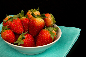 Red fresh strawberry in a bowl on black background.