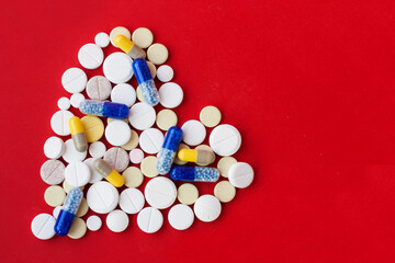Heap of colorful pills in the shape of a heart, tablets and capsules onwhite background. Drug prescription for treatment medication health care concept, top view with copy space