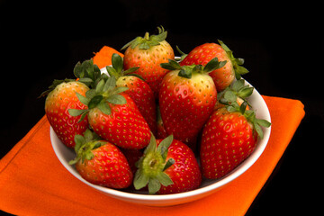 Red fresh strawberry in a bowl on black background.