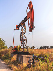 A Small private oil derrick pumps oil on the field. The old handicraft oil rig in the background of the creative industrial design.