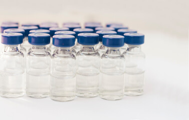 Glass medicine bottles with injection fluid with blue aluminium caps and syringe for vaccination. Cancer, painand diabetestreatment, pharmaceutical medicine concept.