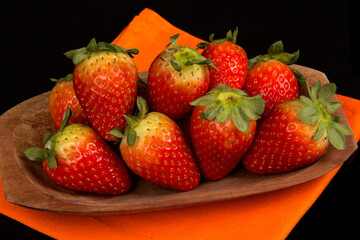 Red fresh strawberry in a bowl on black background.