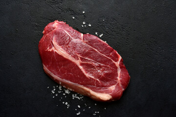 Raw organic marbled beef steak with salt and pepper. Top view with copy space.