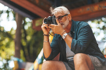 Fototapeta Elderly man's hobby is photography. Retirement travel, outdoor activities. Adventures in life of senior people. obraz
