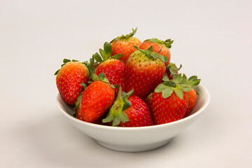Red fresh strawberry in a bowl on white background.