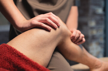 A male masseur massages the calf muscle to a male athlete in a professional massage salon. Sports massage in 4k