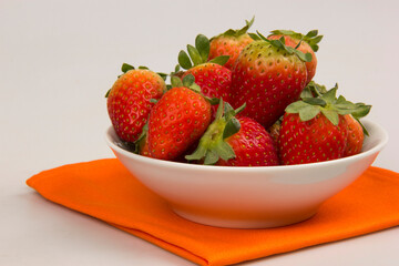 Red fresh strawberry in a bowl on white background.