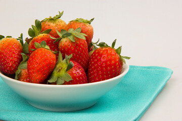 Red fresh strawberry in a bowl on white background.