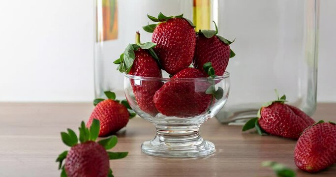 Fresh strawberries in a bowl with glass jars in the background (zoon in).
