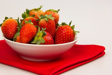 Red fresh strawberry in a bowl on white background.