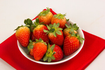 Red fresh strawberry in a bowl on white background.