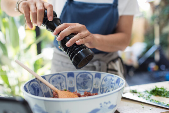 Close Up Woman With Pepper Grinder Cooking In Kitchen