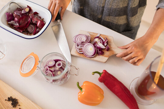 Woman slicing and preserving red onions at kitchen counter