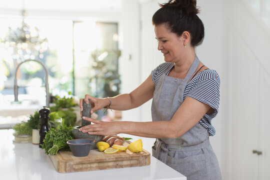 Woman cooking with mortar and pestle at cutting board in kitchen