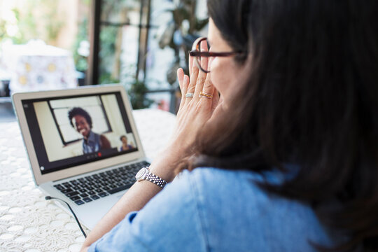 Woman video conferencing with colleagues at laptop screen