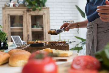 Woman cooking cheeseburgers in kitchen