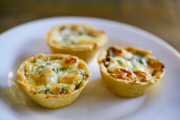 Brazilian gastronomy. Cheese and dried meat pies with arugula in handmade dish on wooden table.