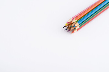 Colored sharpened pencils in the upper right corner on a white sheet of paper