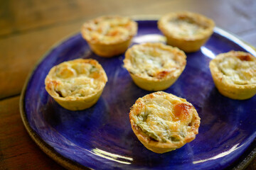 Brazilian gastronomy. Cheese and dried meat pies with arugula in handmade dish on wooden table.