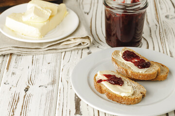 Slice of fresh bread with butter and jam on table