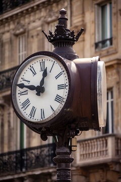 An old clock on a light pole tells time in Paris, France.