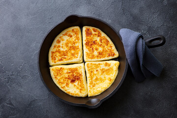 Traditional Scottish tattie potato scones in cast iron pan. Dark background. Close up. Top view.