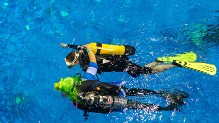 Diving instructor and students. Instructor teaches students to dive in the swimming pool. Scuba...